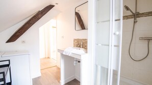 A modern bathroom with a shower, a sink, and a mirror. There is a wooden beam on the ceiling and a view of a hallway. - Le Quai des Marais - Coeur d'Amboise (Amboise)
