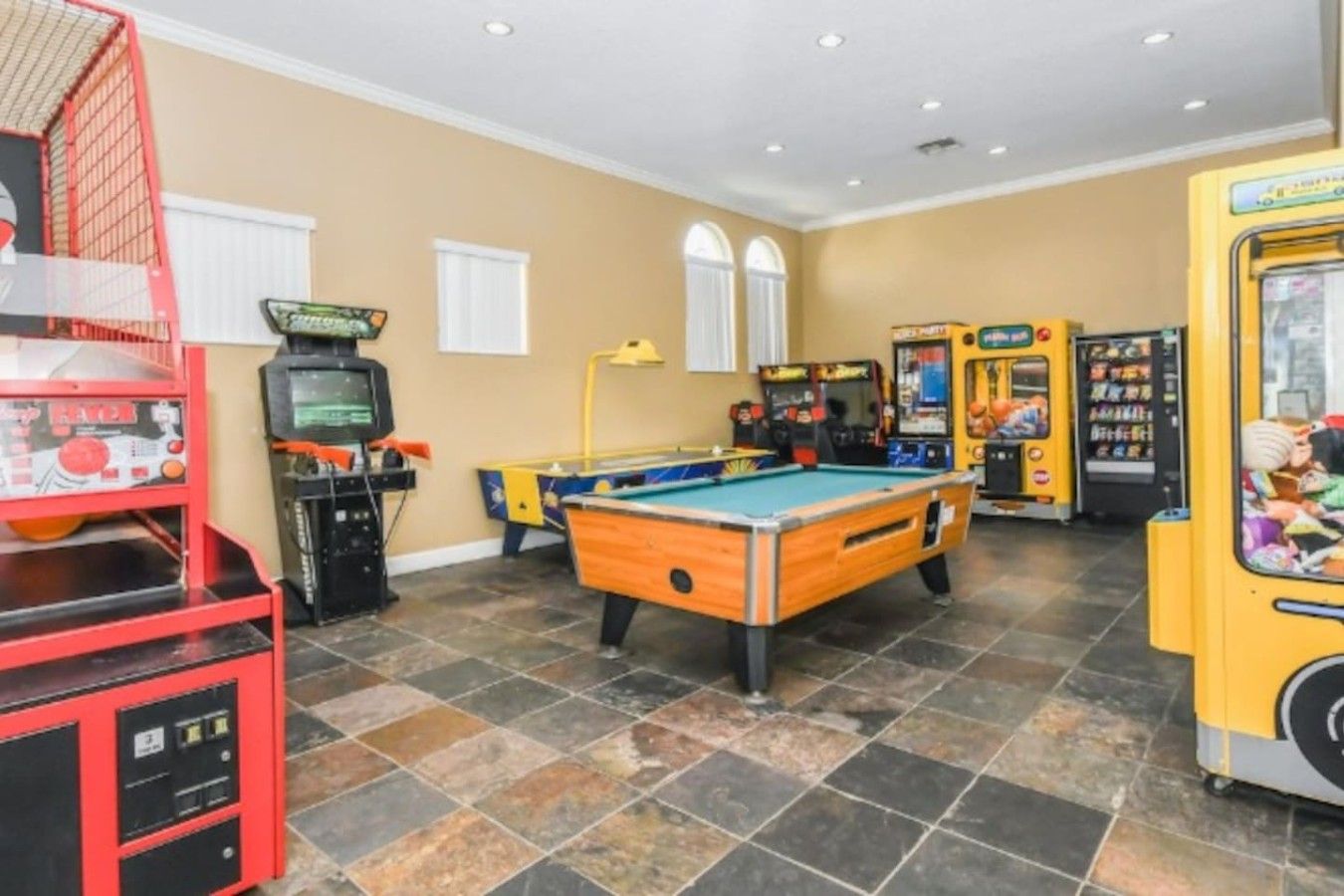 A recreational room with a pool table, arcade games, and a jukebox.