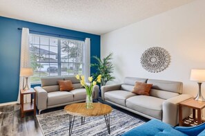 A living room with two sofas, a coffee table, and a decorative wall piece.