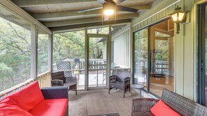 Eine überdachte Veranda mit Korbmöbeln, einem Deckenventilator und Blick ins Freie.
