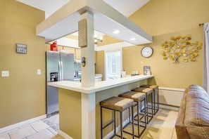 A kitchen with a bar area, a clock, and a wall-mounted decoration. - 2 Decks, Pool Access! Osage Beach Family Retreat (Osage Beach)