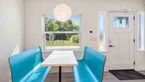 A room with a white door, a window with blinds, a table with two chairs, and a hanging light fixture. - Perfect & Cozy Home in A+ Location (Saint Petersburg)