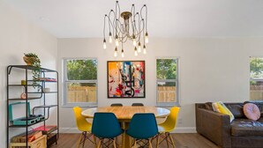 A dining area with a wooden table, yellow chairs, and a modern chandelier. - Perfect & Cozy Home in A+ Location (Saint Petersburg)