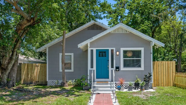 A single-story house with a blue front door, a small porch, and a white picket fence. - Perfect & Cozy Home in A+ Location (Saint Petersburg)