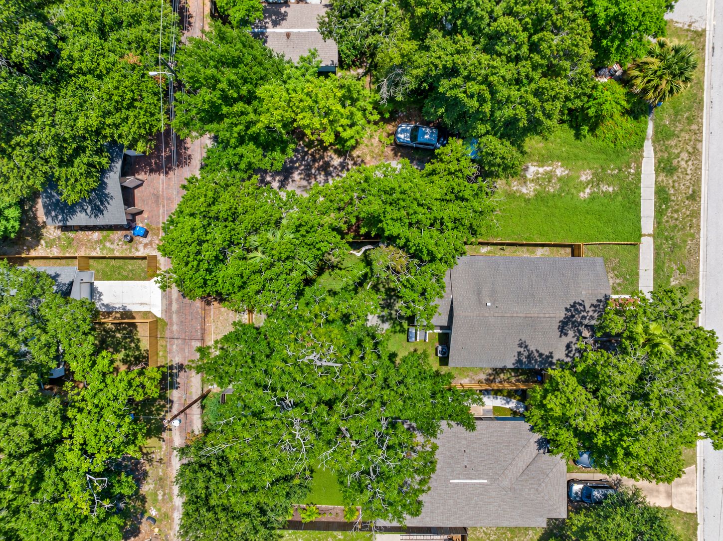 An aerial view of a residential area with houses, trees, and a clear sky.