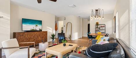 Una sala de estar moderna con un sofá, un sillón, una mesa de centro y un televisor montado en la pared.
