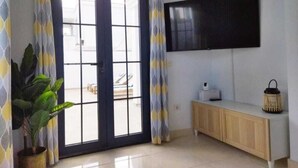 A room with a sliding glass door, a flat-screen TV mounted on the wall, a wooden console table, and a potted plant. - Villa with private pool a stone's throw from the beach (Playa blanca)