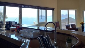 Une cuisine dotée d’un grand îlot central, d’un évier et offrant une vue sur la mer.
