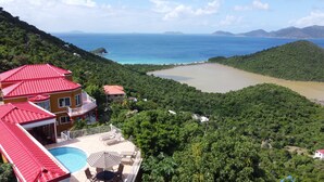 Un complexe hôtelier doté d’une piscine, de chaises longues et offrant une vue sur la mer et les montagnes.