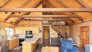 Une cuisine spacieuse avec des meubles en bois, un îlot central et un coin repas comprenant un canapé bleu et un divan marron.