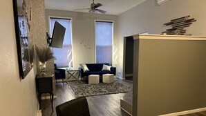 A modern living room with a glass dining table, dark sofas, and a large mirror. - Modern condo with jacuzzi in the heart of downtown. (Wabasha)