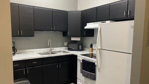 A modern kitchen with black cabinets, a white refrigerator, a microwave, and a stainless steel sink. - Modern condo with jacuzzi in the heart of downtown. (Wabasha)