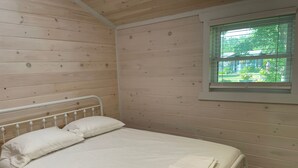 A single bed with white bedding in a room with wooden walls and a window. - Modern Cottage on the Water - Newly Renovated! (Dashwood)