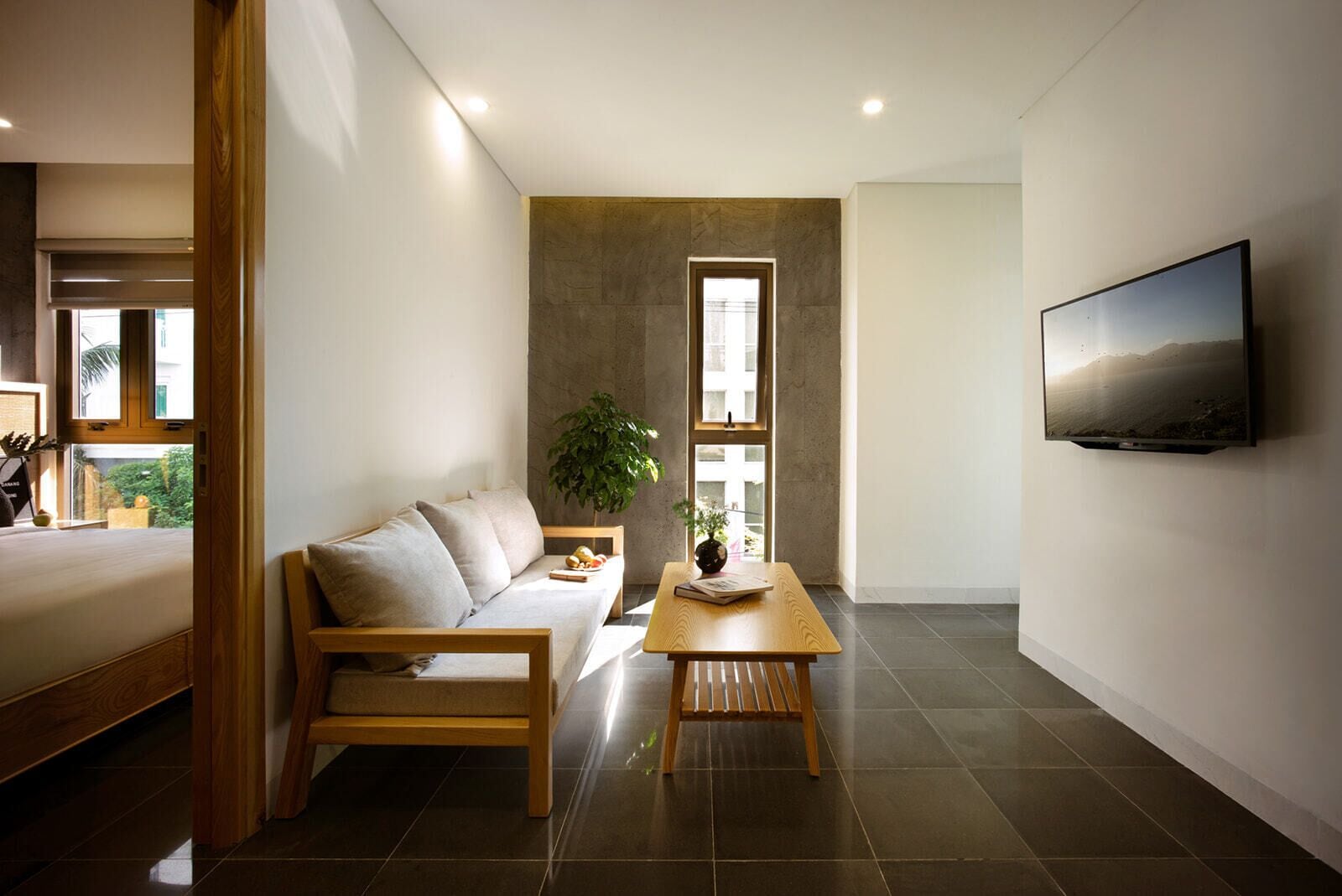 A modern living room with a sofa, coffee table, and a TV mounted on the wall.