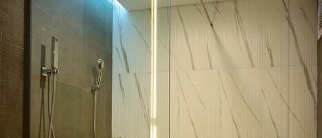A modern bathroom with a freestanding bathtub, a glass shower enclosure, and a marble-patterned wall.