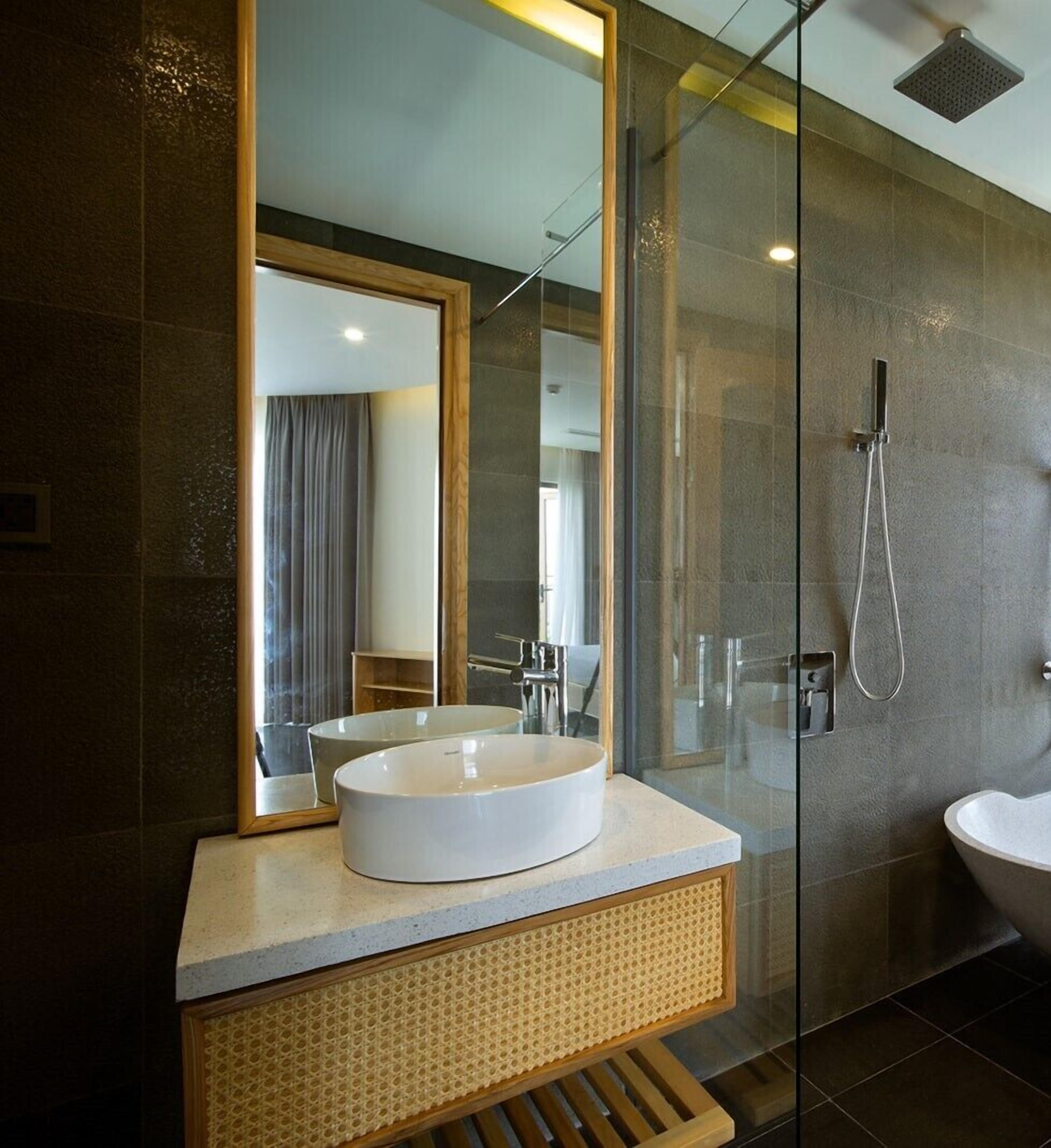 A modern bathroom with a large mirror, a white sink, and a glass-enclosed shower area.