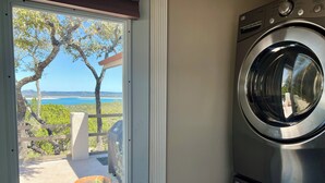 Ein Waschraum mit Blick auf einen Strand und Bäume durch ein Fenster.