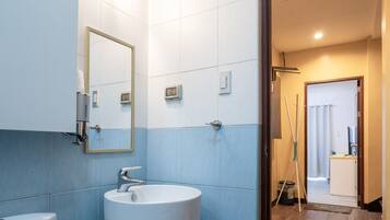 A bathroom with a toilet, sink, and mirror. There is a door leading to another room.