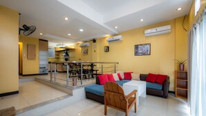 A modern living room with a sofa, wooden chair, and a dining area with a table and chairs.
