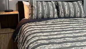 Un dormitorio con una cama, una mesita de noche, una lámpara y una obra de arte de una motocicleta en la pared.