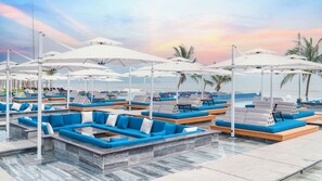 A poolside area with lounge chairs and umbrellas, a clear view of the ocean, and a sunset sky. - Mikazuki Villas - The Ryokan (Da Nang)