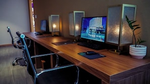 A conference room with a long wooden table, a desktop computer, a keyboard, a mouse, and a potted plant. - Mikazuki Villas - The Ryokan (Da Nang)