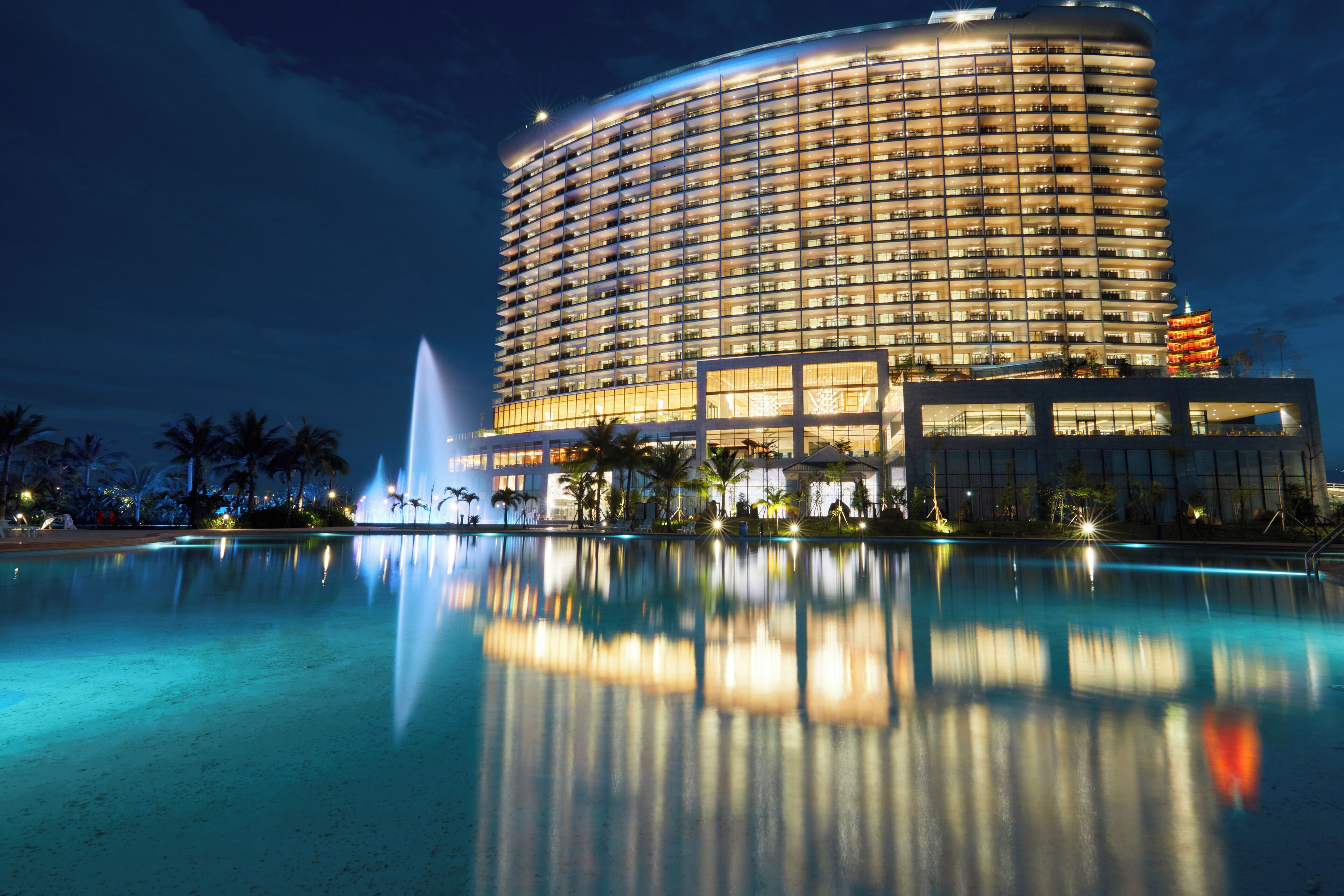 A large hotel with a reflective pool and a fountain.