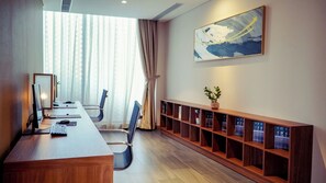 A conference room with a long wooden table, chairs, a computer, and a bookshelf with books. - Mikazuki Villas - The Ryokan (Da Nang)