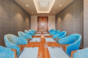 A conference room with a long table, blue chairs, and a decorative wooden door. - Mikazuki Villas - The Ryokan (Da Nang)
