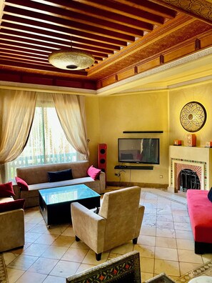 Una sala de estar con sofá, sillones, una mesa de centro, televisor y chimenea.