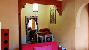 Une pièce chaleureuse avec un canapé rouge, un plafond en bois et un miroir au mur.