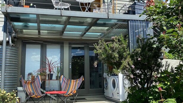 Et toetagers hus med balkon, udendørs siddepladser og plantekasser.