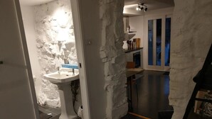 Et badeværelse med en hvid vask, en stenvæg og et vindue med blå rammer.