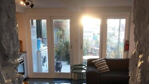 En stue med sofa, sofabord og udsigt gennem en glasdør til et vaskerum.