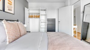 Une chambre à coucher moderne avec un lit, une armoire et un miroir.