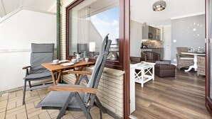 A modern living room with a dining area, a kitchen, and a balcony with outdoor seating. - SyltMomente - 2-room apartment close to the beach: balcony, parking space, WLAN. Pets (Sylt)