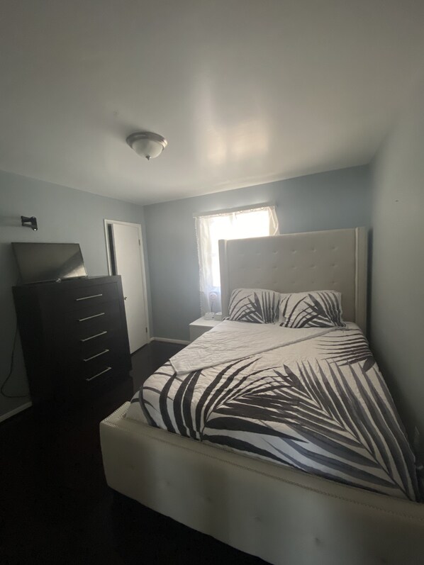 A bedroom with a bed, a dresser, and a ceiling light. - Akeem's  guest house (Silver Spring)