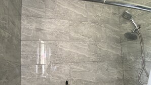 Une douche équipée d’un pommeau de douche à main et d’un flexible de douche.