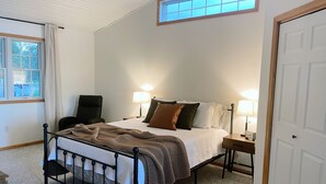A bedroom with a bed, two bedside tables, a chair, a window, and a door. - Maple Haven :: Modern, year round home on Maple Lake in Mentor, MN (Mentor)