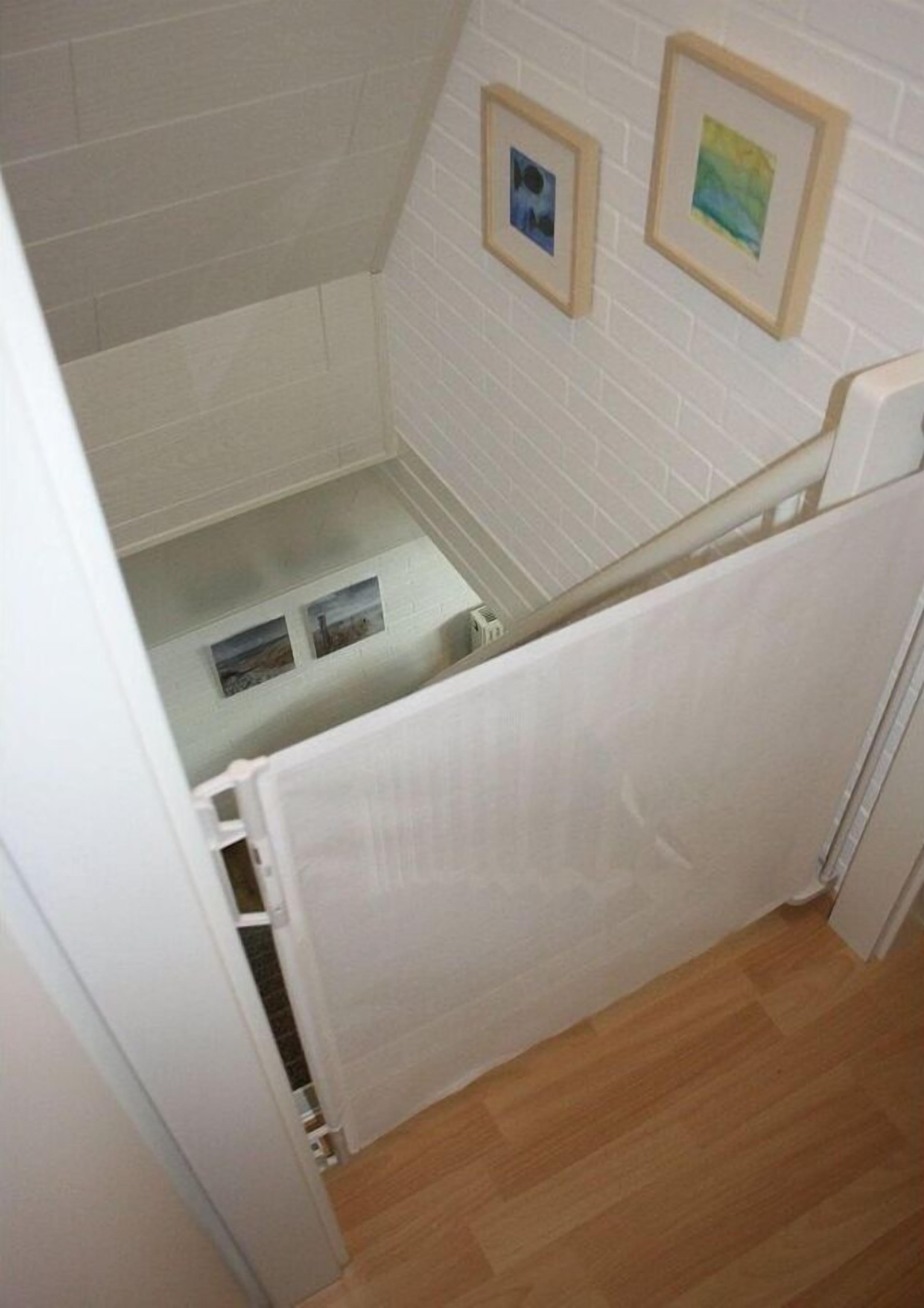 A bathroom with white tiled walls, a wooden floor, and a shower area.
