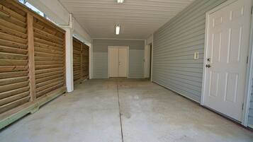 Eine Garage mit Überdachung, Betonboden, Holzwänden und einer weißen Tür.