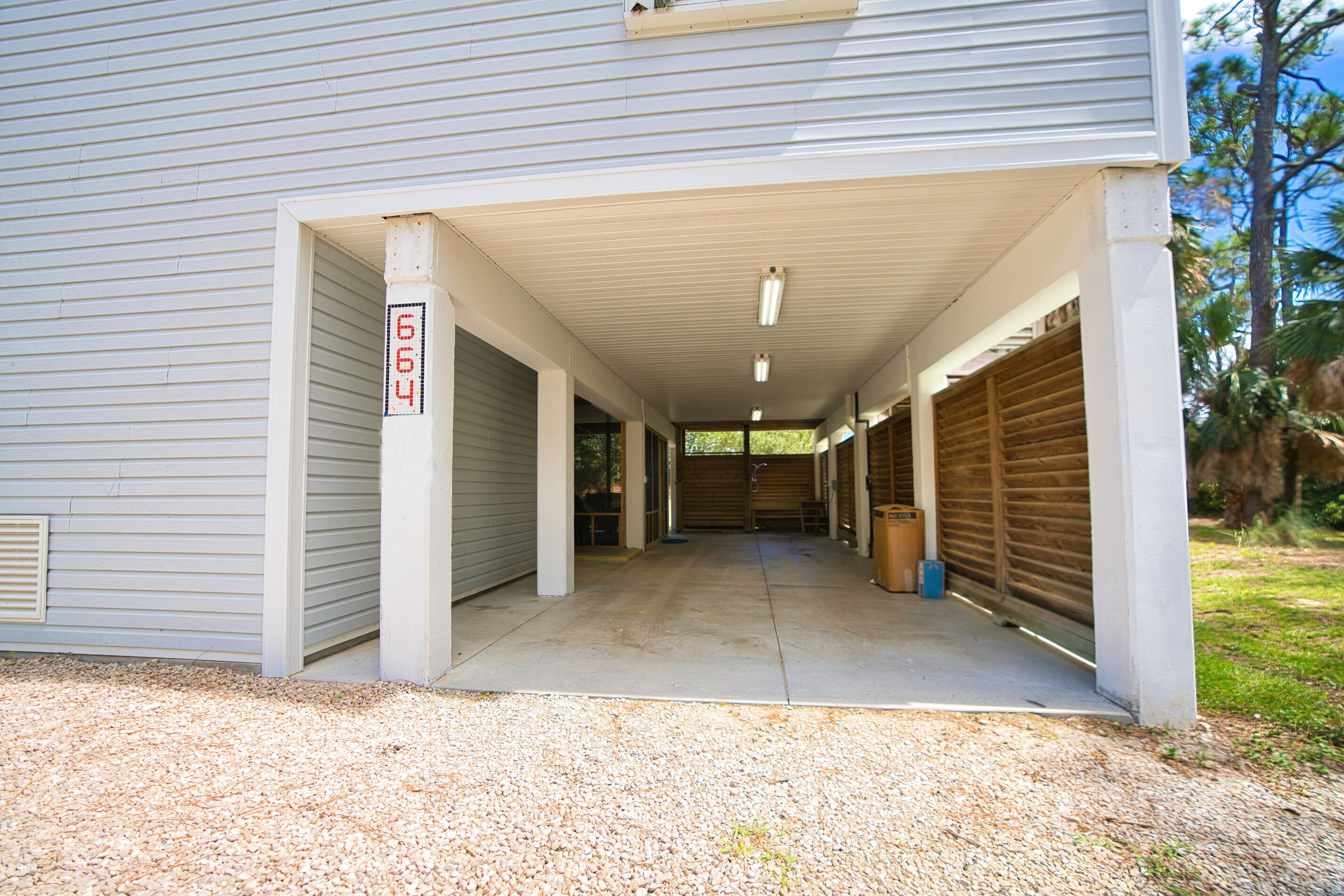 A covered garage entrance with a concrete floor and a gravel driveway.