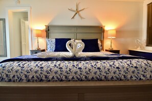 Un lit recouvert d’une couvre-lit à motifs floraux, deux serviettes en forme de cœur et une étoile de mer décorative au-dessus de la tête de lit.