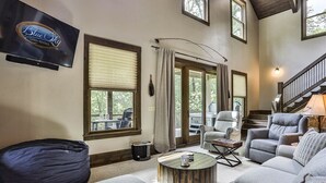A living room with a sofa, armchairs, a coffee table, a bean bag, and a television. - FightingTown Escape | Blue Ridge, GA (McCaysville)