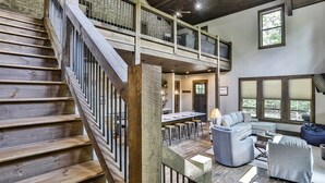 A spacious living area with a wooden staircase, a dining area, and a seating area with a sofa and chairs. - FightingTown Escape | Blue Ridge, GA (McCaysville)