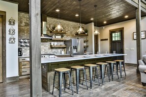 Une cuisine dotée d’un îlot central, de tabourets de bar, de luminaires suspendus et d’un mur en briques.