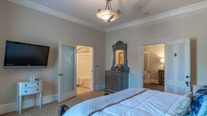 Un dormitorio con cama, televisor, cómoda y espejo.