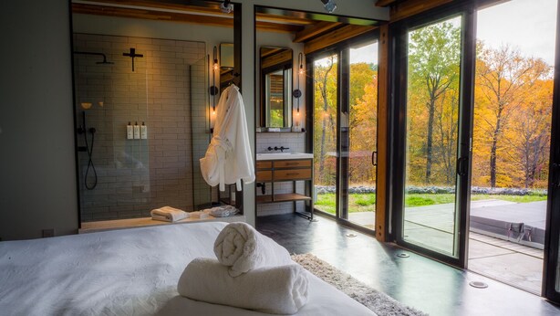 A modern bedroom with a large bed, a walk-in shower, and a bathroom with a sink and mirror. - Hudson Ridge / Hot Tub, Fire Pit & Fireplace (Hudson)