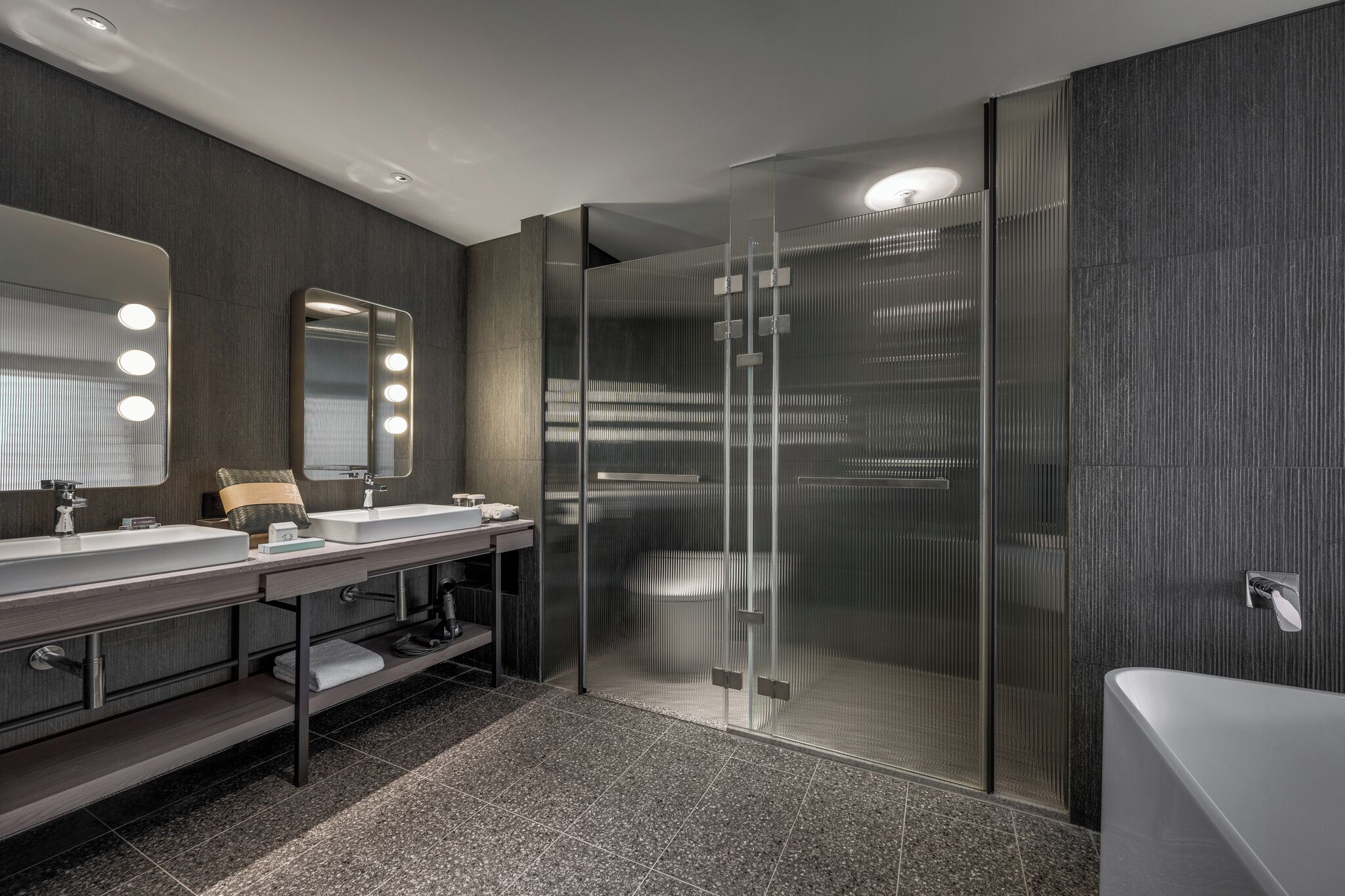 A modern bathroom with a glass-enclosed shower, a vanity with a mirror and lights, and a bathtub.