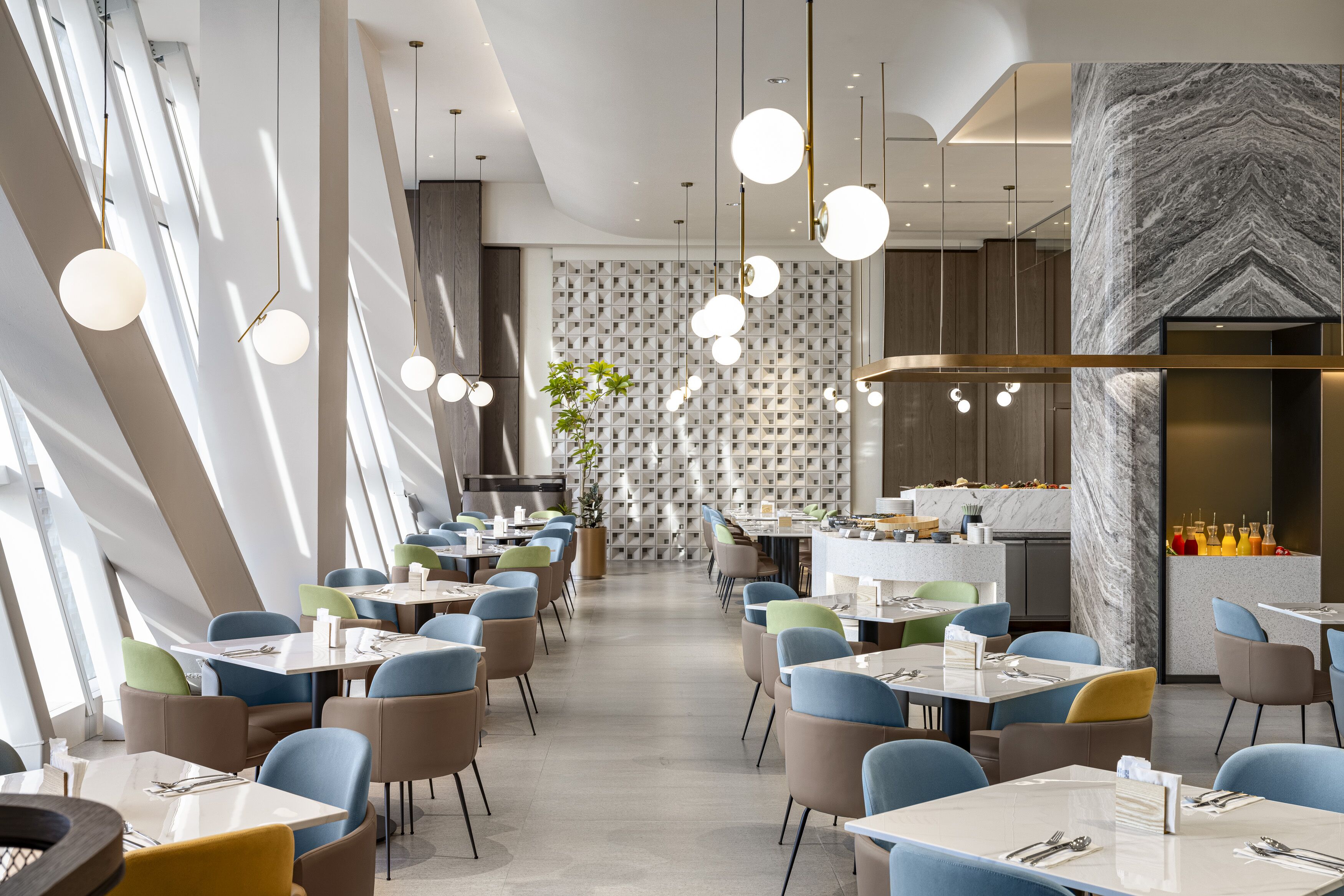 A modern restaurant with a long dining area, round tables, and chairs.